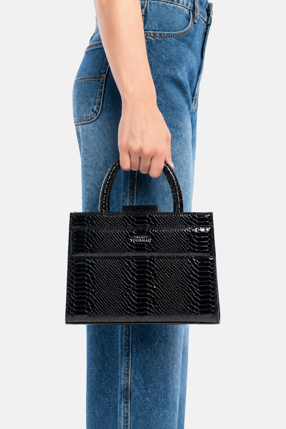 Mini tote bag serane nera pitonata, portata a mano dalla modella. TWENTYFOURHAITCH.
