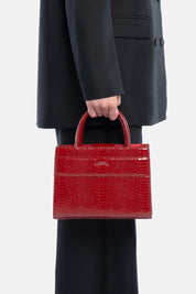Mini tote bag serane rossa pitonata, portata a mano dalla modella. TWENTYFOURHAITCH.